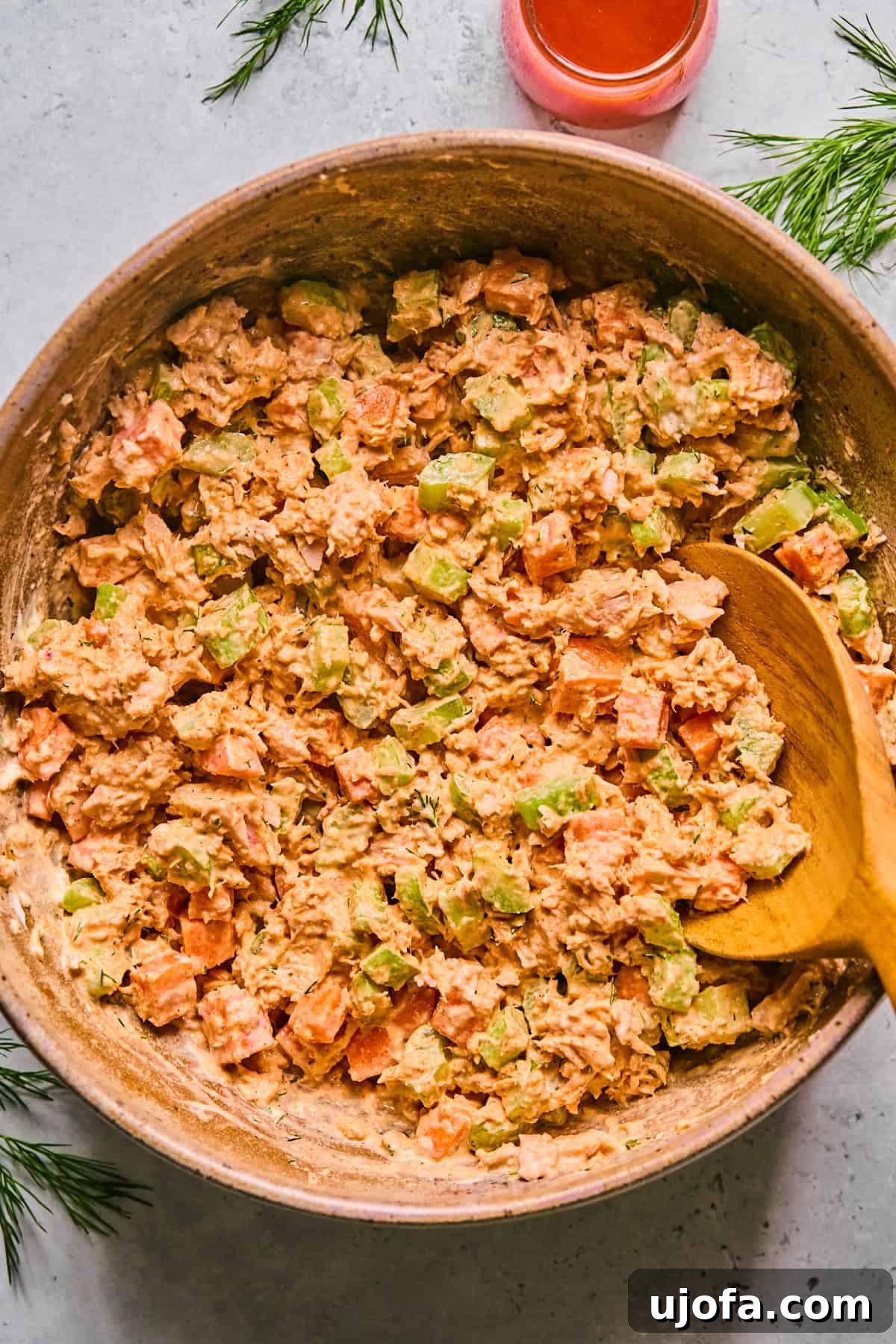 Creamy buffalo tuna salad in a pink bowl with a wooden spoon, ready to serve