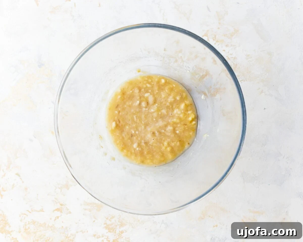Wholesome Banana Oat Cookies 5 Mashed ripe bananas in a glass mixing bowl on a light countertop, ready to be used in cookie batter.