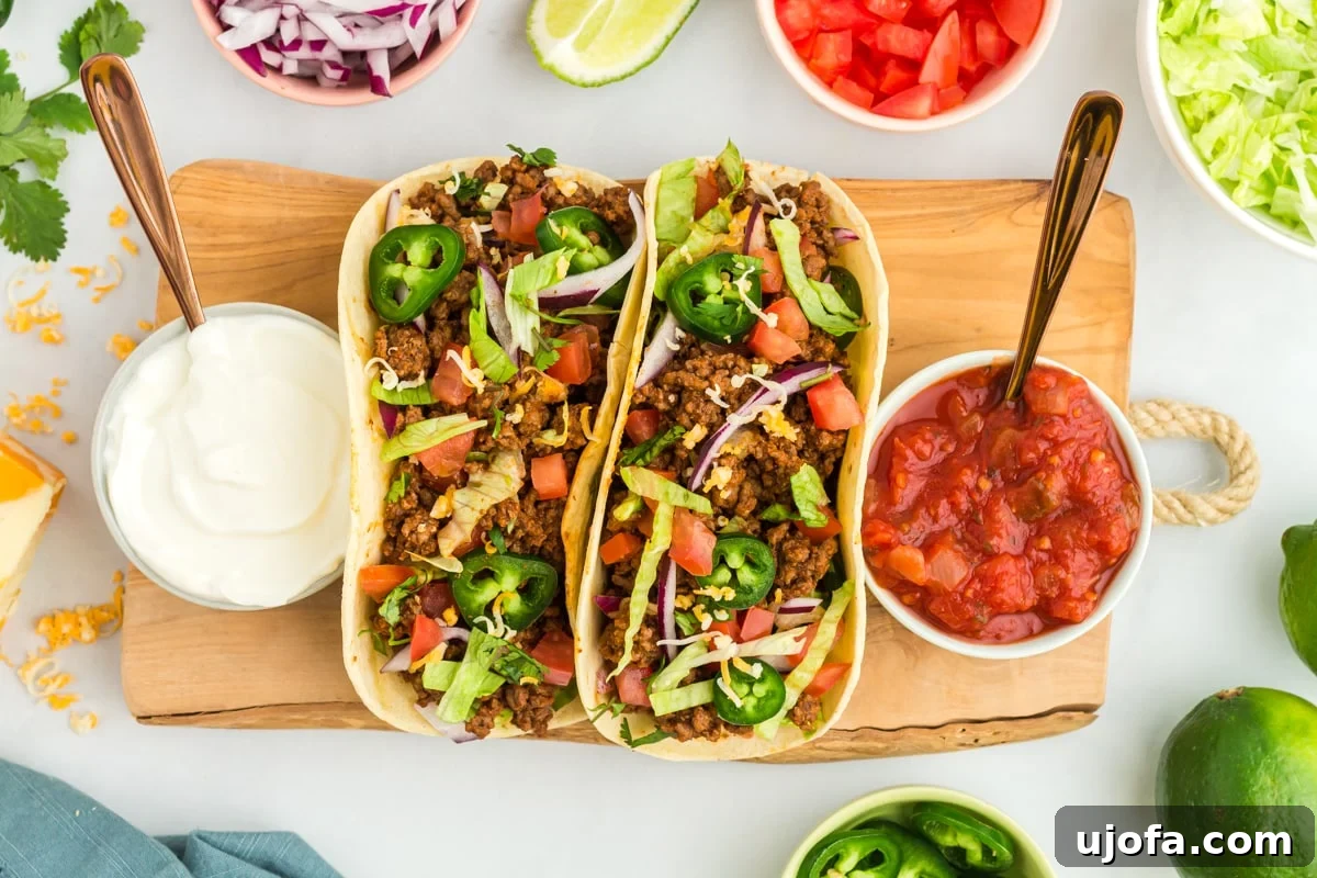 Guilt-Free Taco Night 6 overhead view of 2 gluten-free tacos on a wooden cutting board with taco sauce and sour cream.