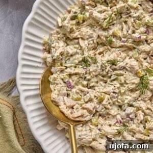 dill pickle chicken salad in a bowl with a gold and wooden serving spoon