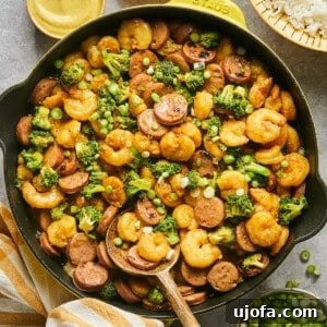 Hot honey shrimp and sausage stir fry with broccoli in a yellow Staub skillet.