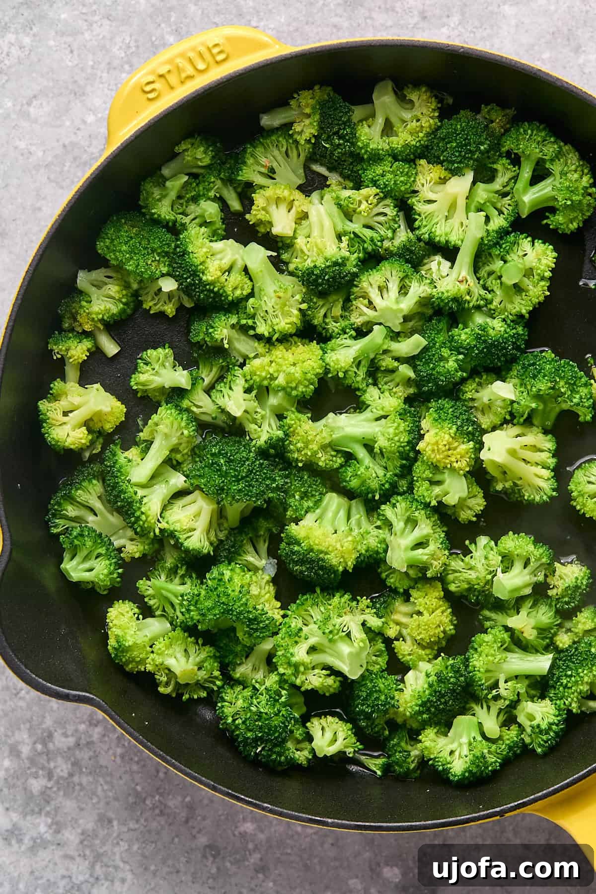Perfectly steamed, bright green broccoli florets in a skillet after being covered.