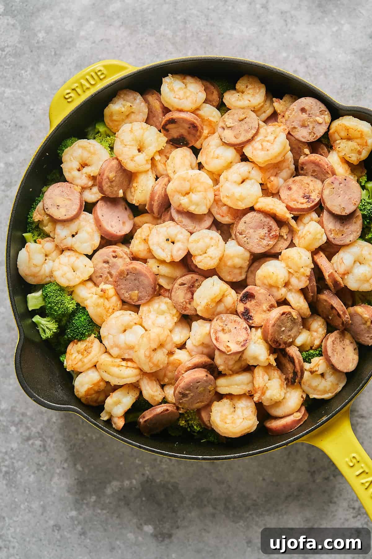 Cooked shrimp and sausage returned to the skillet, resting on a bed of steamed broccoli.