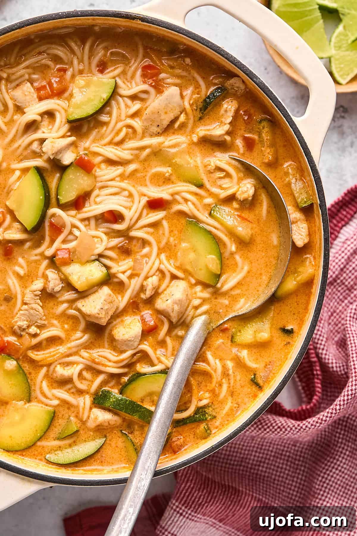 A close-up shot of rich and creamy red curry soup in a large pot, with a serving ladle invitingly resting, highlighting the vibrant color and texture.