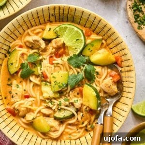 Red Thai Curry Noodle Soup in a bowl with 2 wooden spoons, ready to serve.