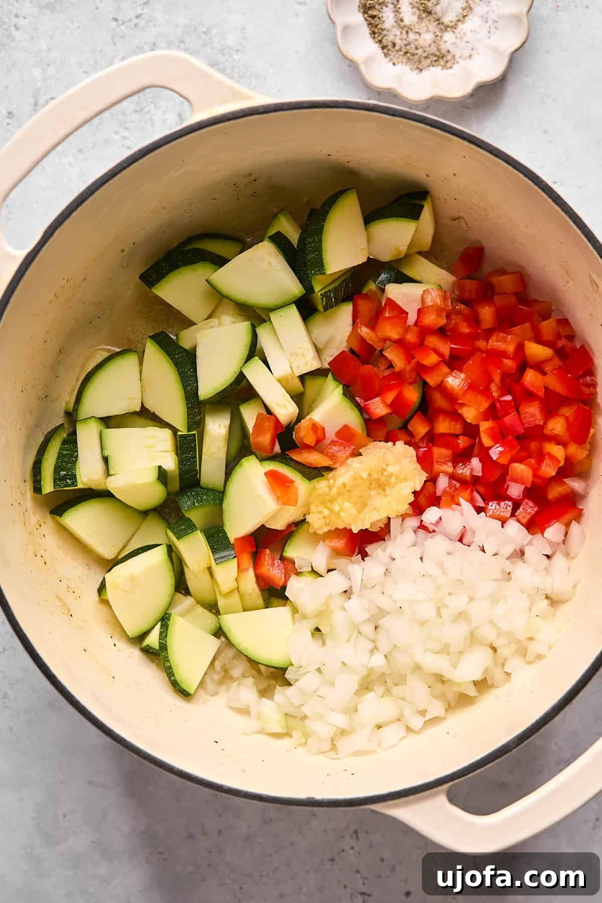 Diced zucchini, red bell pepper, and onion being sautéed in the same pot, infused with the residual flavors from the cooked chicken.
