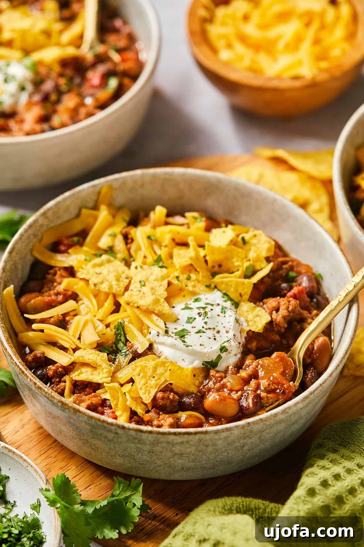 Ultimate Slow Cooker Taco Chili Recipe 2 A bowl of slow cooker taco chili topped with crunchy tortilla chips, a dollop of sour cream, fresh cilantro, and shredded cheese, ready to be enjoyed.