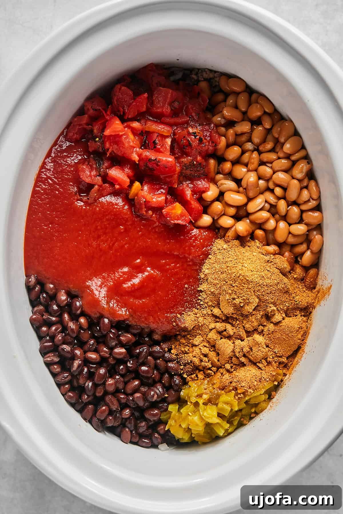 Ultimate Slow Cooker Taco Chili Recipe 7 All the ingredients for taco chili, including beans, tomatoes, sauce, broth, and seasoning, added to the slow cooker with the beef and vegetables.
