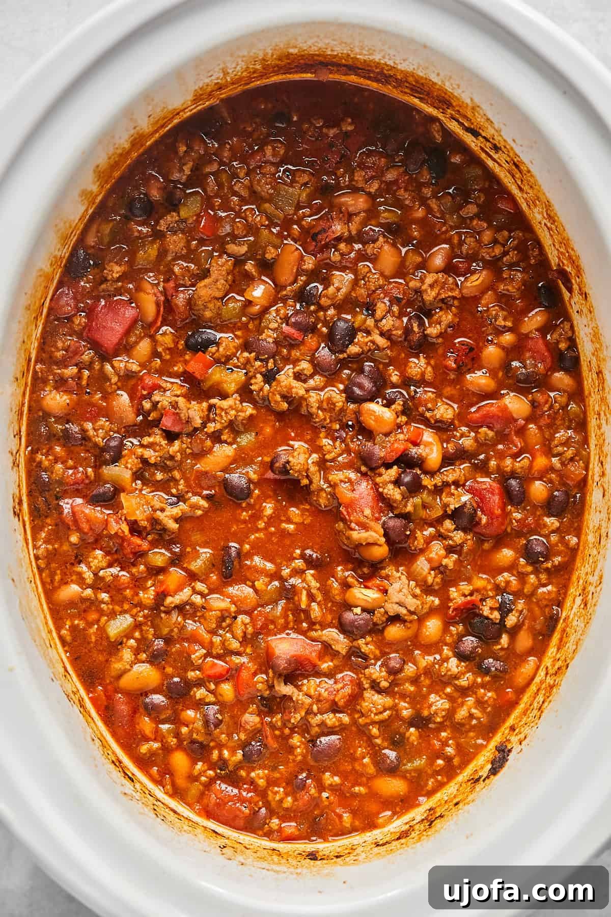 Ultimate Slow Cooker Taco Chili Recipe 9 Cooked chili in a white crock pot, steaming and ready to be served, showcasing its rich texture and color.