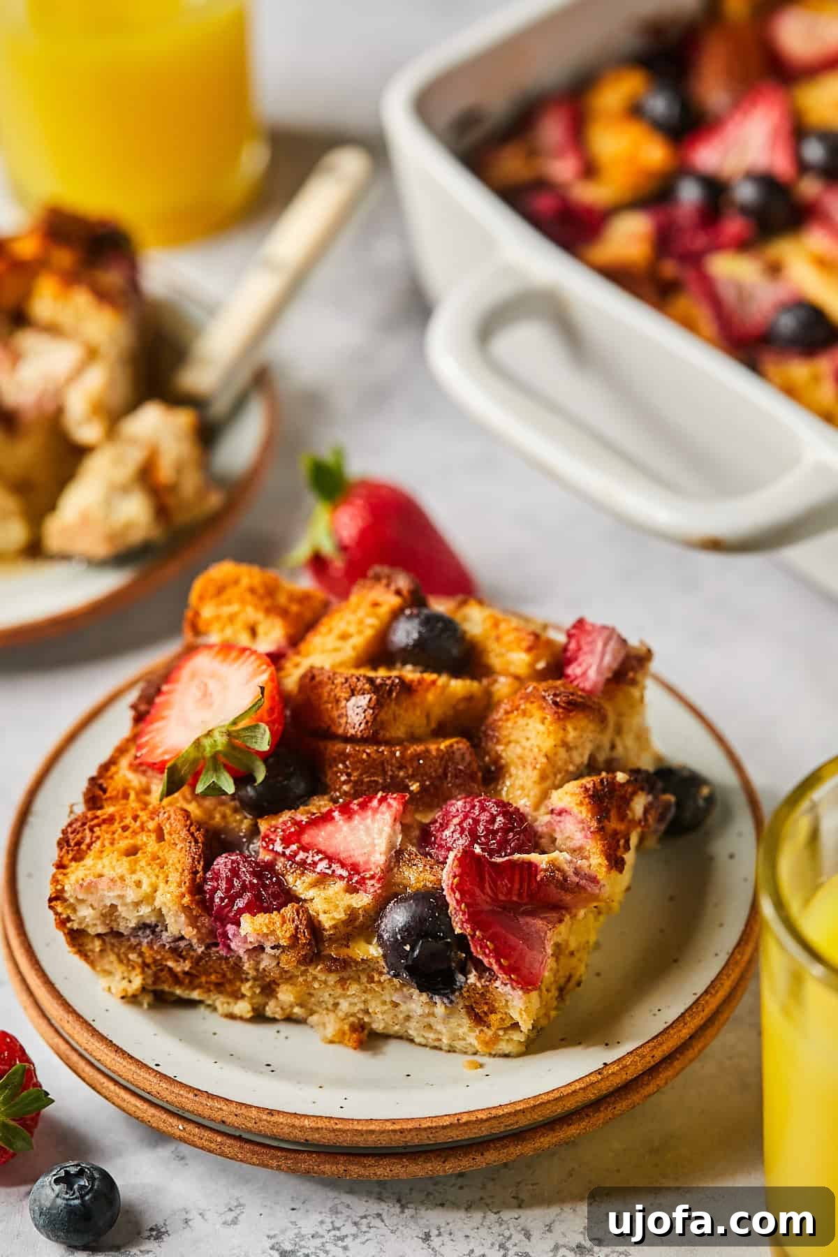 A delectable slice of Protein French Toast Casserole, topped with fresh berries and a drizzle of maple syrup, resting on a pristine white plate.