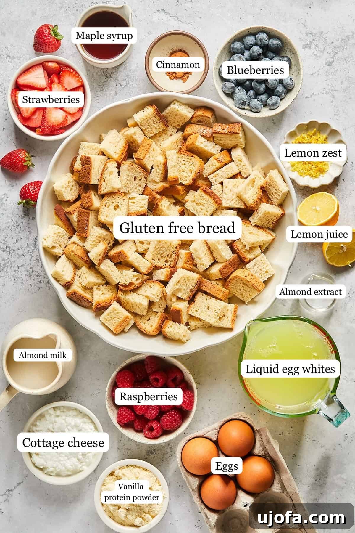 Various recipe ingredients, including bread, berries, eggs, and liquids, neatly arranged in small bowls and clearly labeled.
