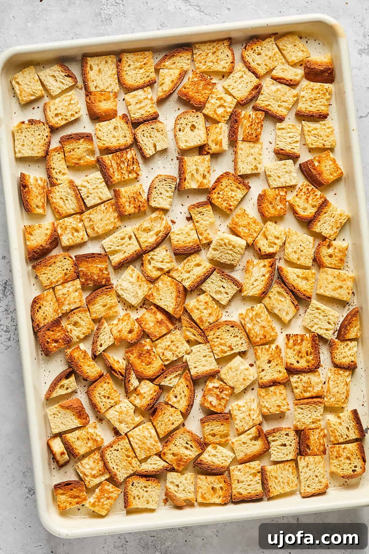 Golden-brown baked bread cubes on a baking pan, slightly toasted for optimal texture.