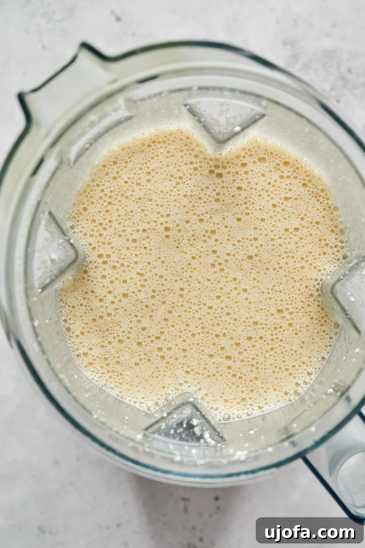 A close-up of the smooth, creamy custard mixture in a blender, ready to be poured over the bread and berries.