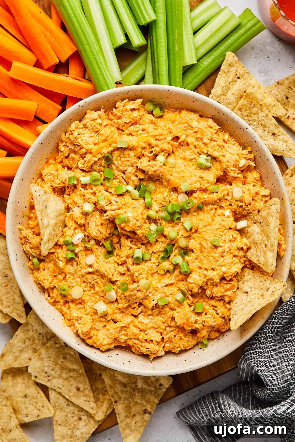 high protein buffalo chicken dip in a bowl topped with green onions