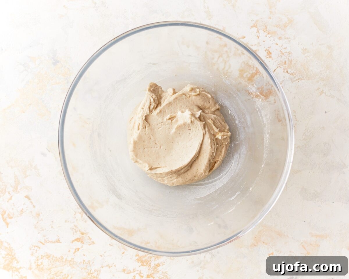 Soft, sticky dough for gluten-free pita bread in a glass mixing bowl after mixing wet and dry ingredients.