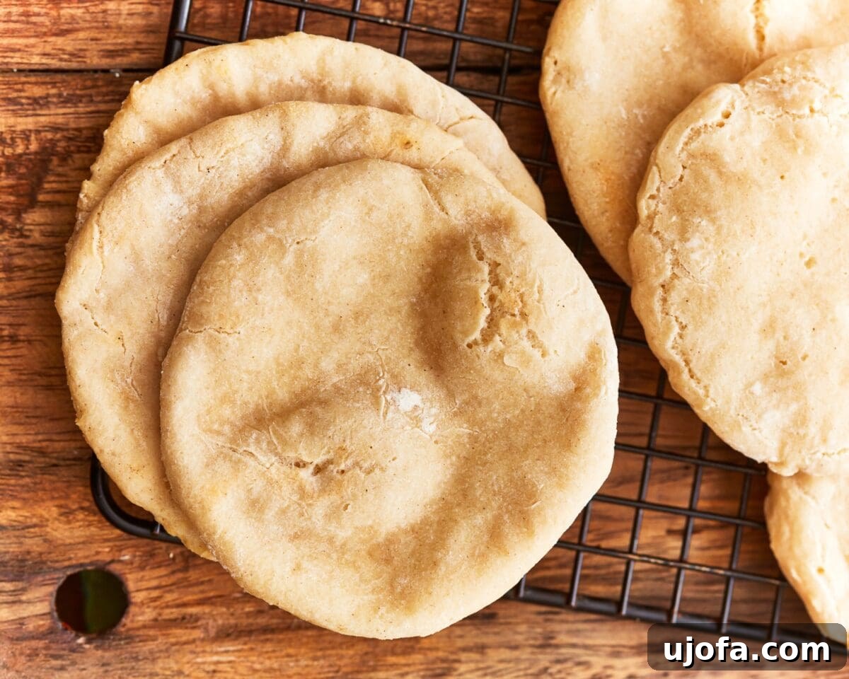 Baked gluten-free pitas resting on a wire rack, showing golden tops and light puffiness.