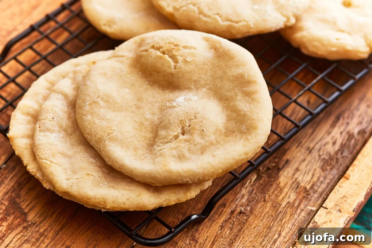 Angled view of a stack of gluten-free pita bread on a cooling rack over a rustic wooden table.
