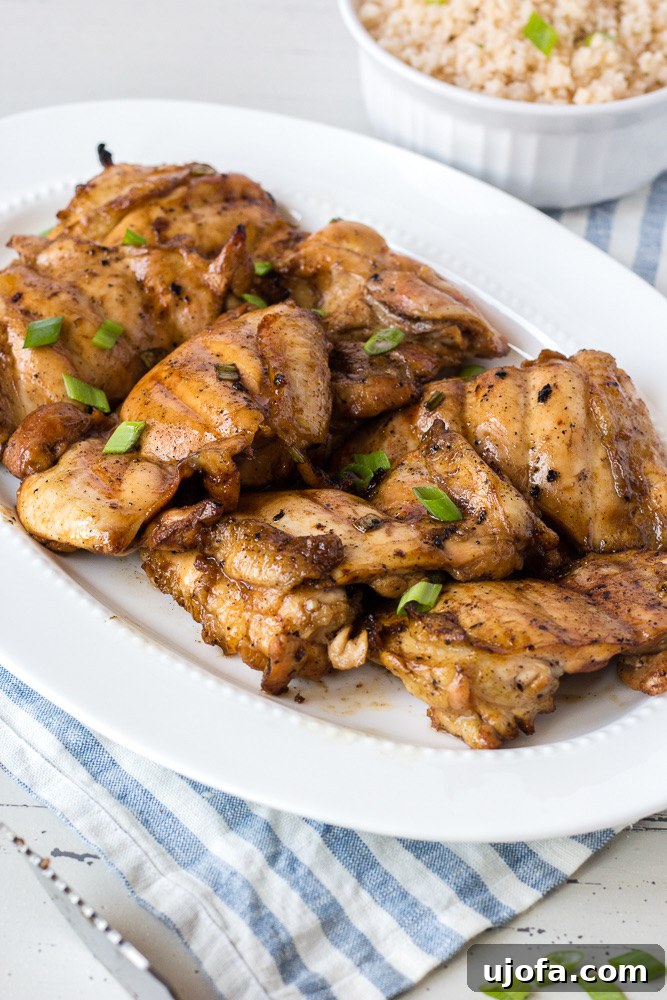 Perfectly grilled teriyaki chicken thighs on a plate with a garnish.