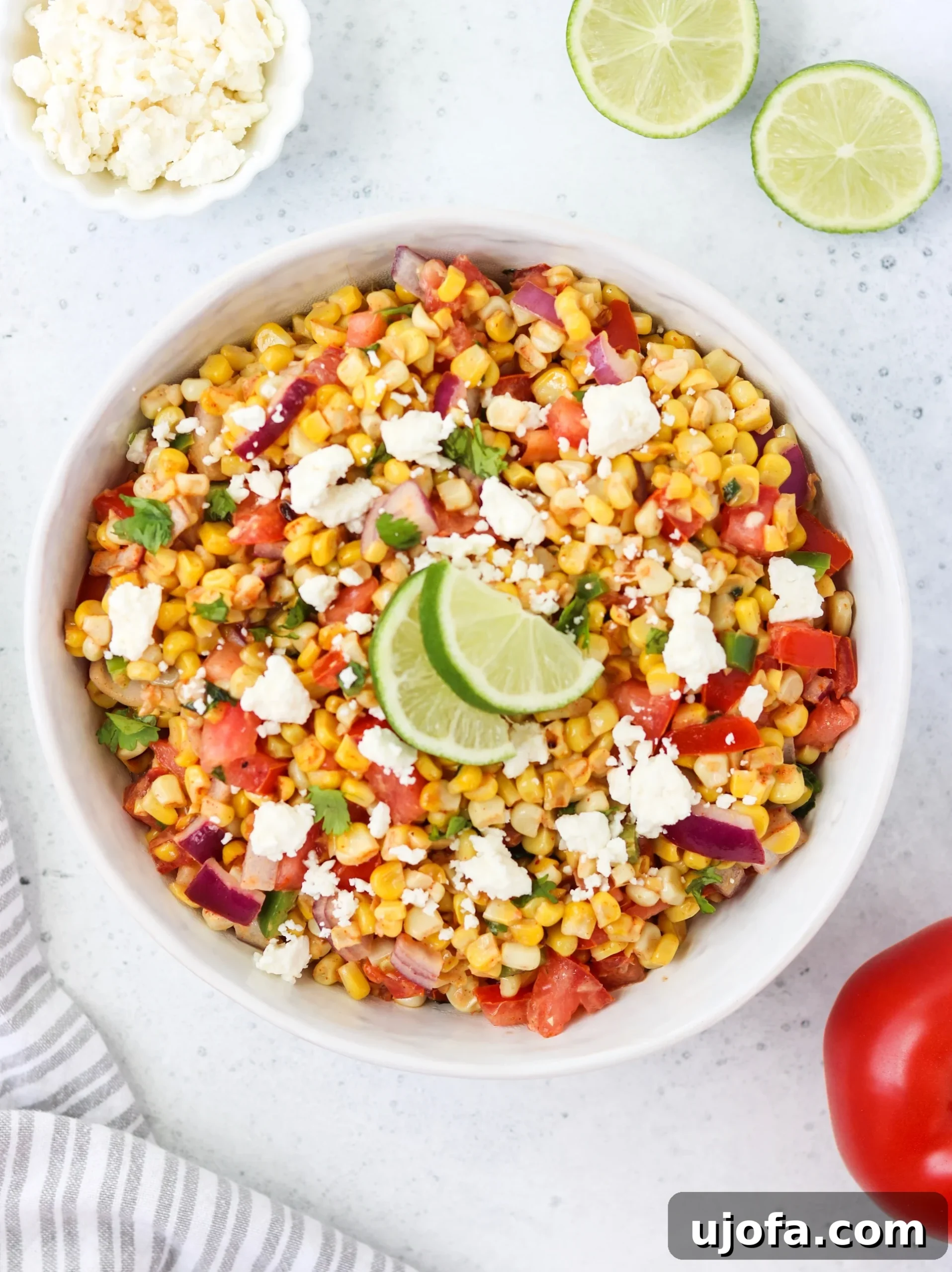 Mexican Street Corn and Tomato Salad in a smaller bowl, garnished with a lime wedge.