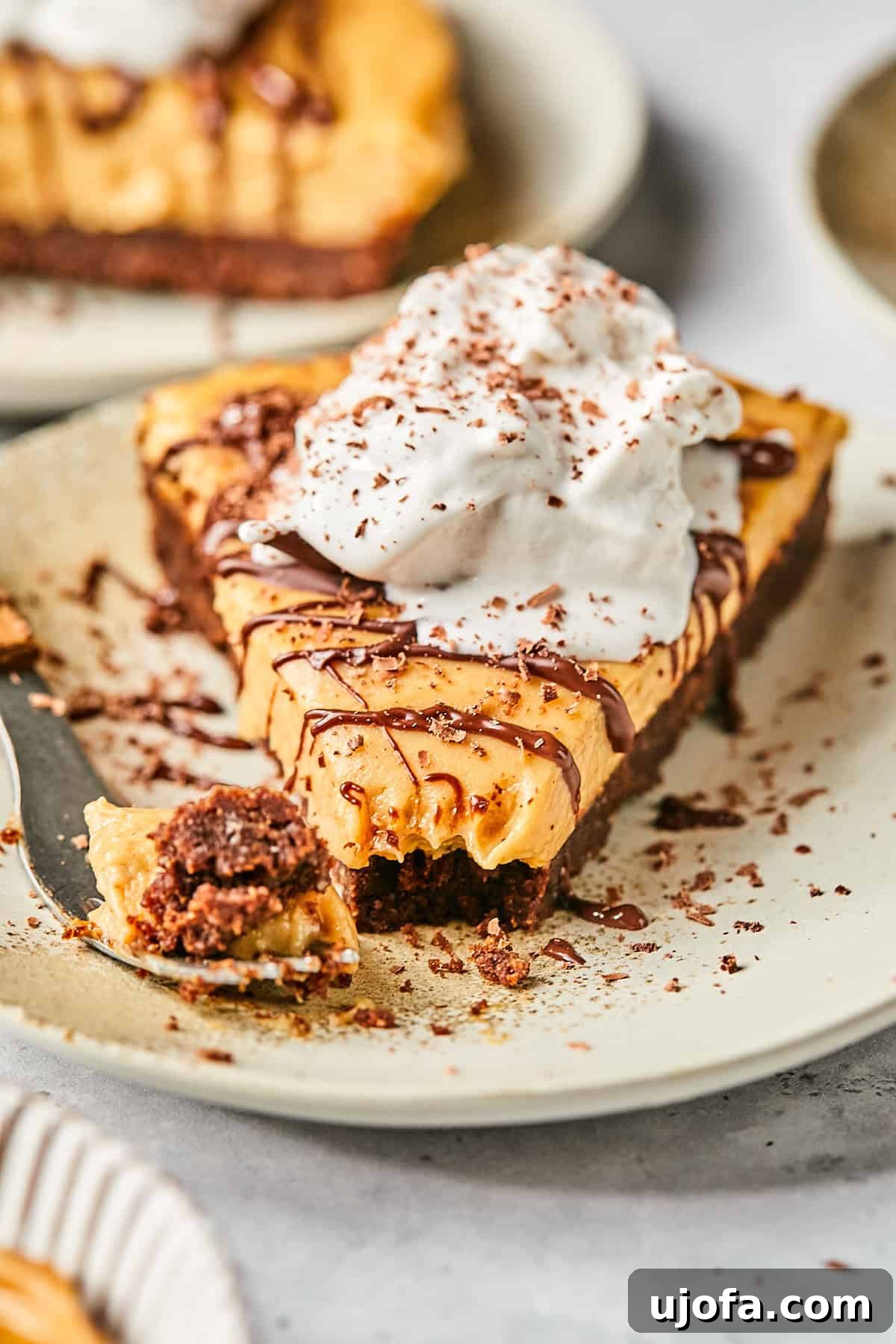 No-Bake Vegan Peanut Butter Bliss 15 A slice of dairy-free peanut butter pie on a plate, with a bite taken out, showing the creamy filling and chocolate crust.