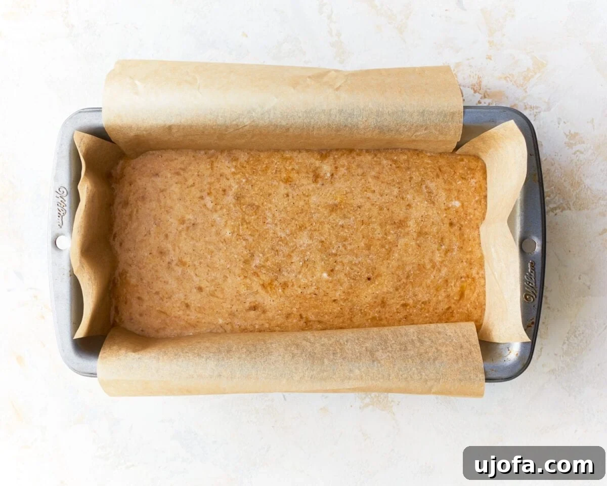 Tropical Coconut Banana Bread 8 coconut flour banana bread batter poured into a loaf tin lined with parchment paper, ready for baking.