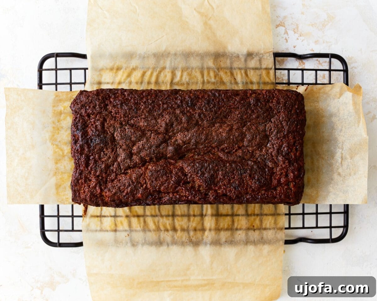 Tropical Coconut Banana Bread 9 Baked and browned coconut flour banana bread on parchment paper resting on a cooling rack, showing a perfectly golden crust.