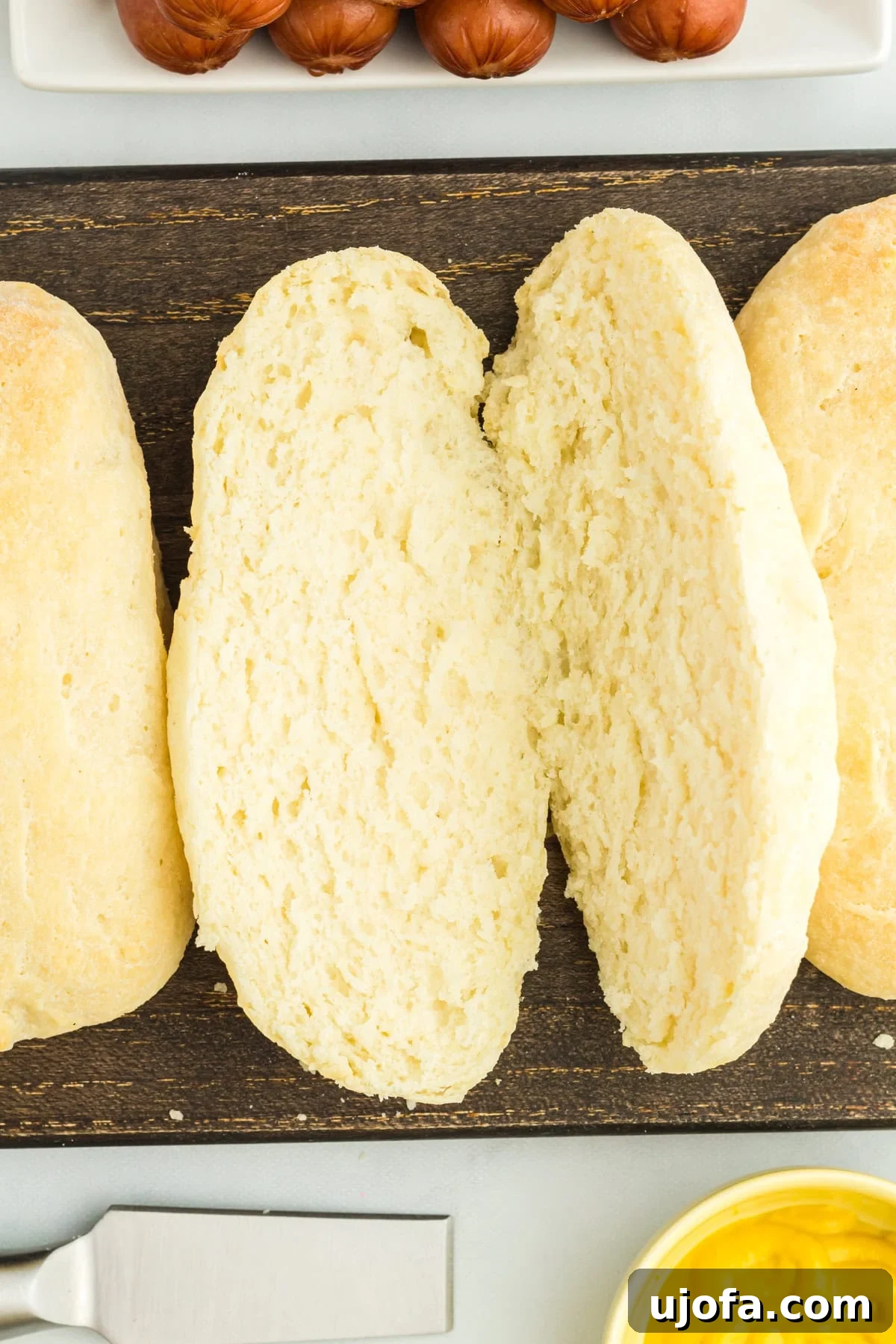 A close-up, overhead view of a freshly baked, cut gluten-free hot dog bun, showcasing its soft interior texture.