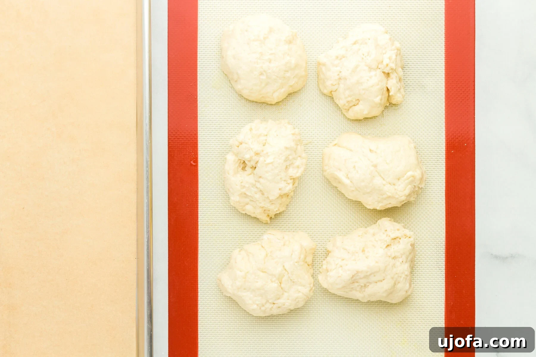 A large mass of gluten-free hot dog bun dough on a work surface, ready for division.