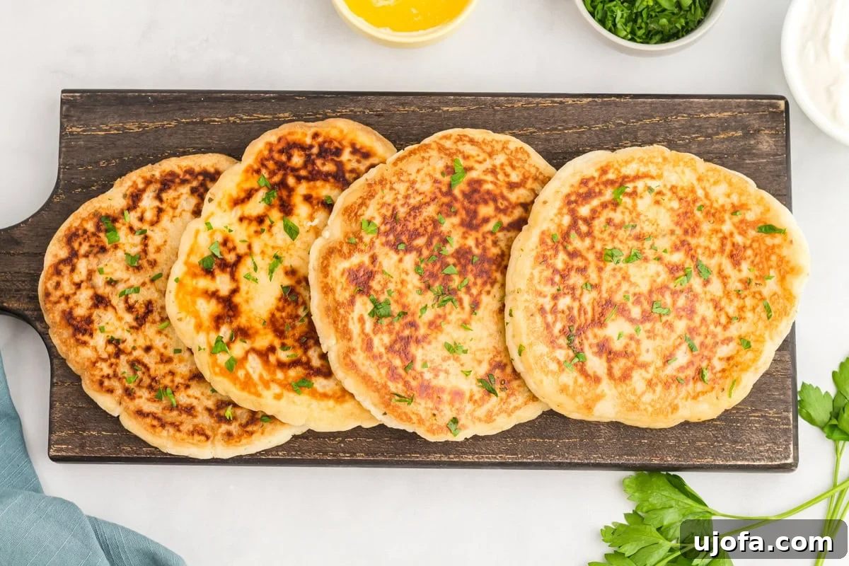 Effortless Gluten-Free Flatbread 13 four gluten-free flatbreads laying on a black serving platter topped with fresh chopped parsley