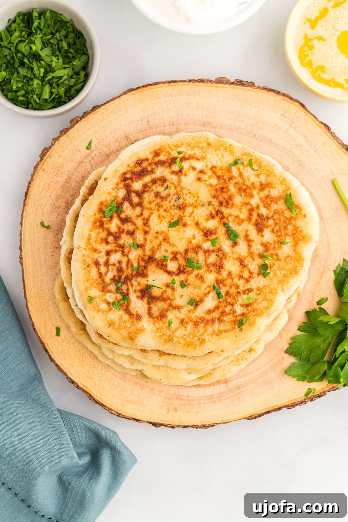 Effortless Gluten-Free Flatbread 5 overhead view of gluten-free flatbread stacked on a wooden stump and garnished with fresh parsley