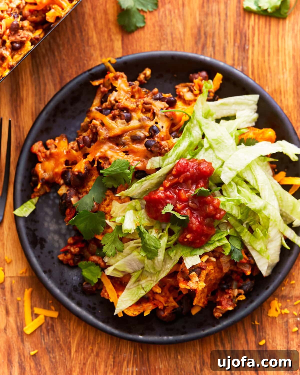 Unbagged Taco Bake 11 A serving of walking taco casserole on a plate, garnished with fresh lettuce and a side of salsa.