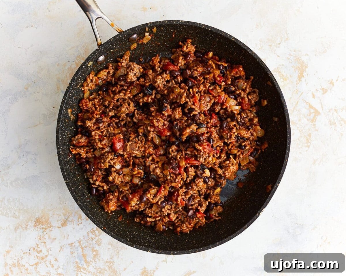 Unbagged Taco Bake 7 Seasoned ground beef with salsa and black beans mixed in a skillet.