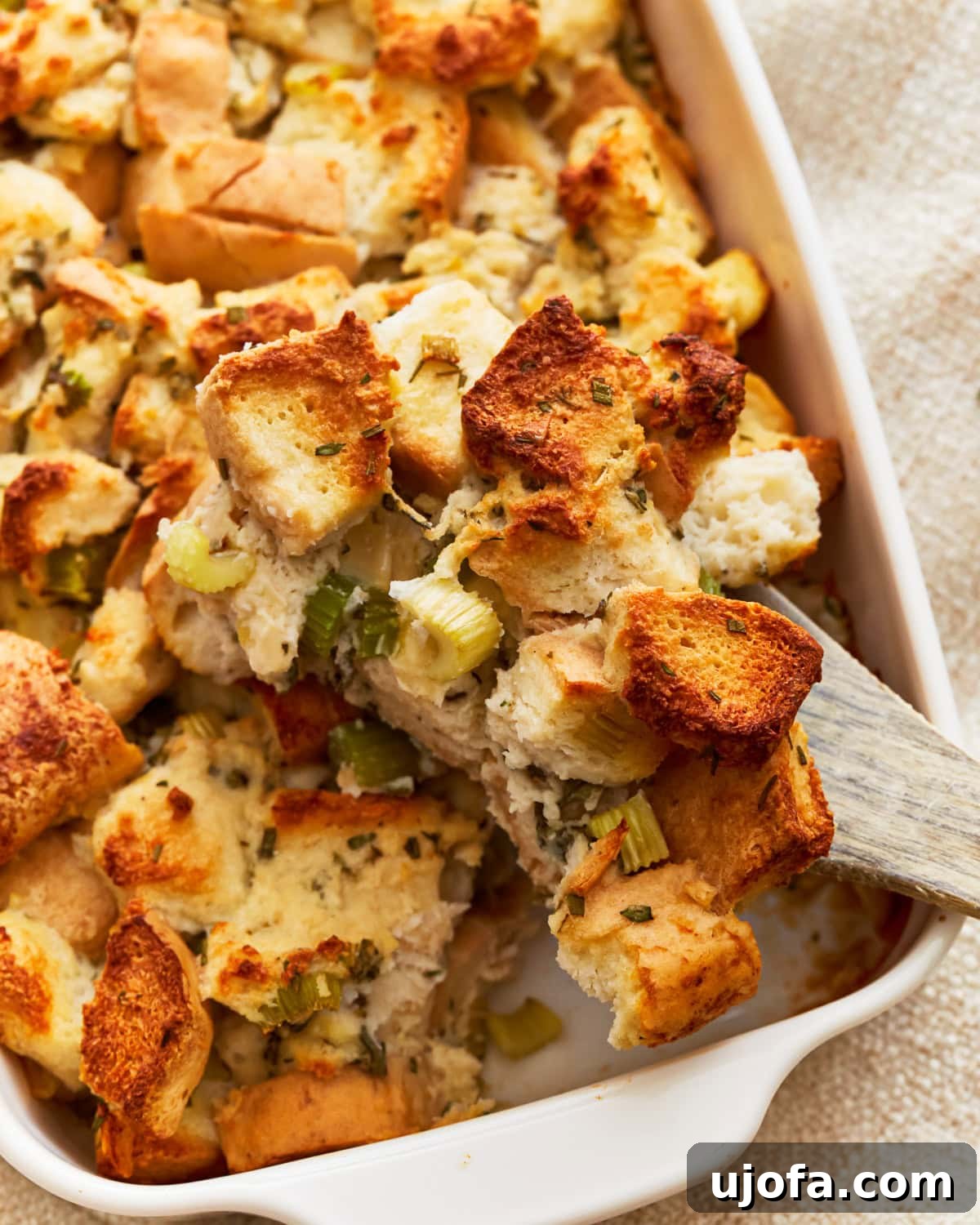 Flavorful Gluten-Free Stuffing 5 A wooden spoon taking a serving of gluten-free stuffing from a baking dish