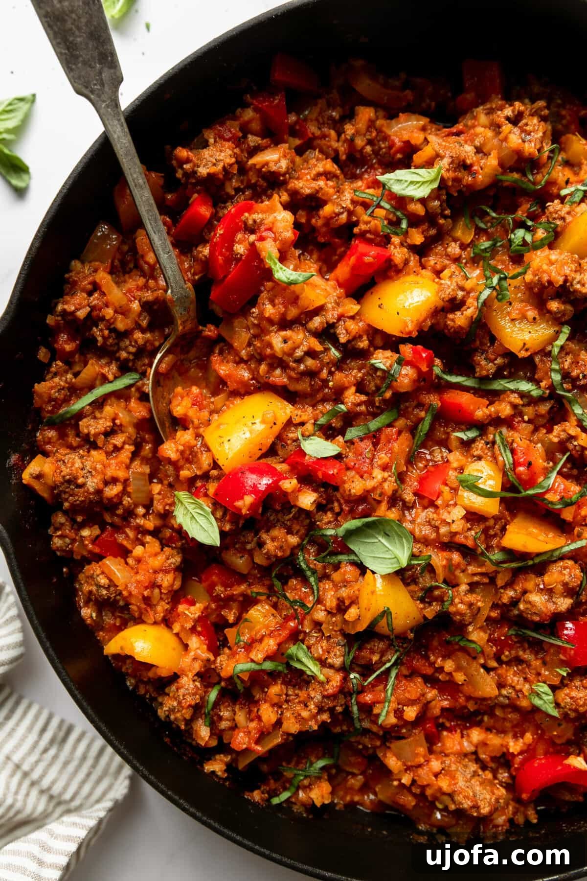 Open-Faced Stuffed Pepper Skillet 5 unstuffed pepper ingredients like cauliflower rice, ground beef, and peppers in a black skillet