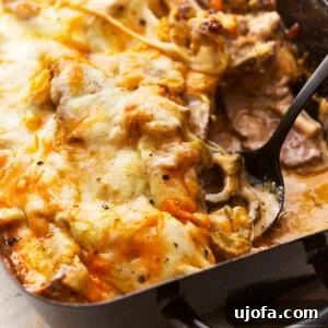 Close up of a spoon scooping philly cheesesteak casserole from a casserole dish.