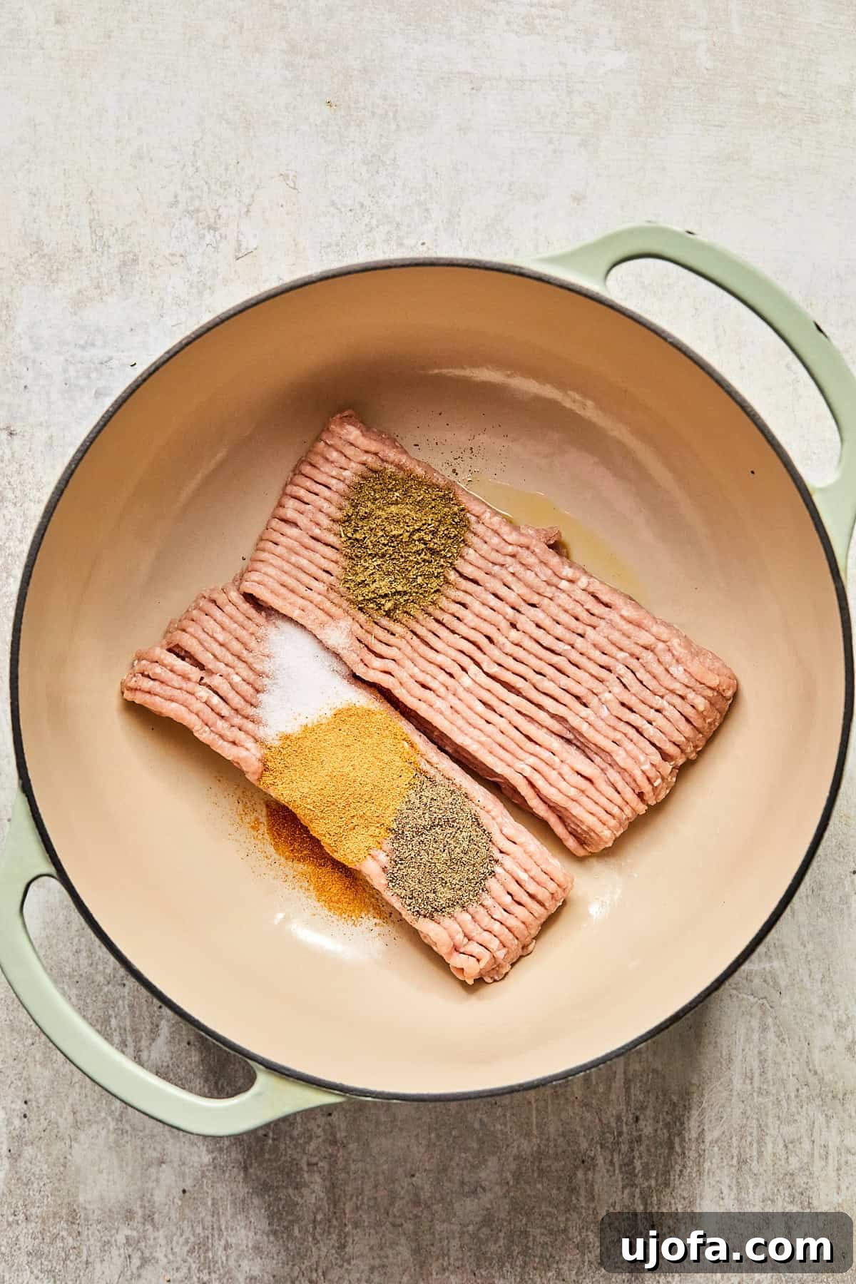Ground turkey and spices being cooked in a large pot, beginning to brown and release their aromas.