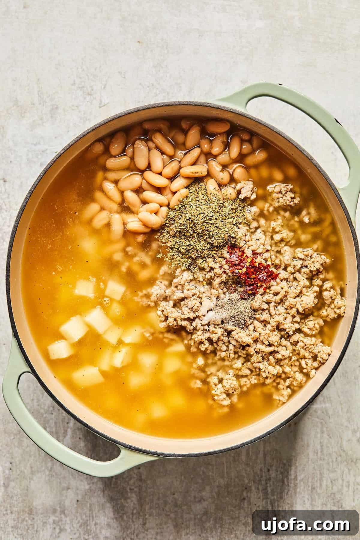 All the core ingredients: cooked ground turkey, cannellini beans, cubed potatoes, broth, and spices, combined in a pot, ready to simmer.
