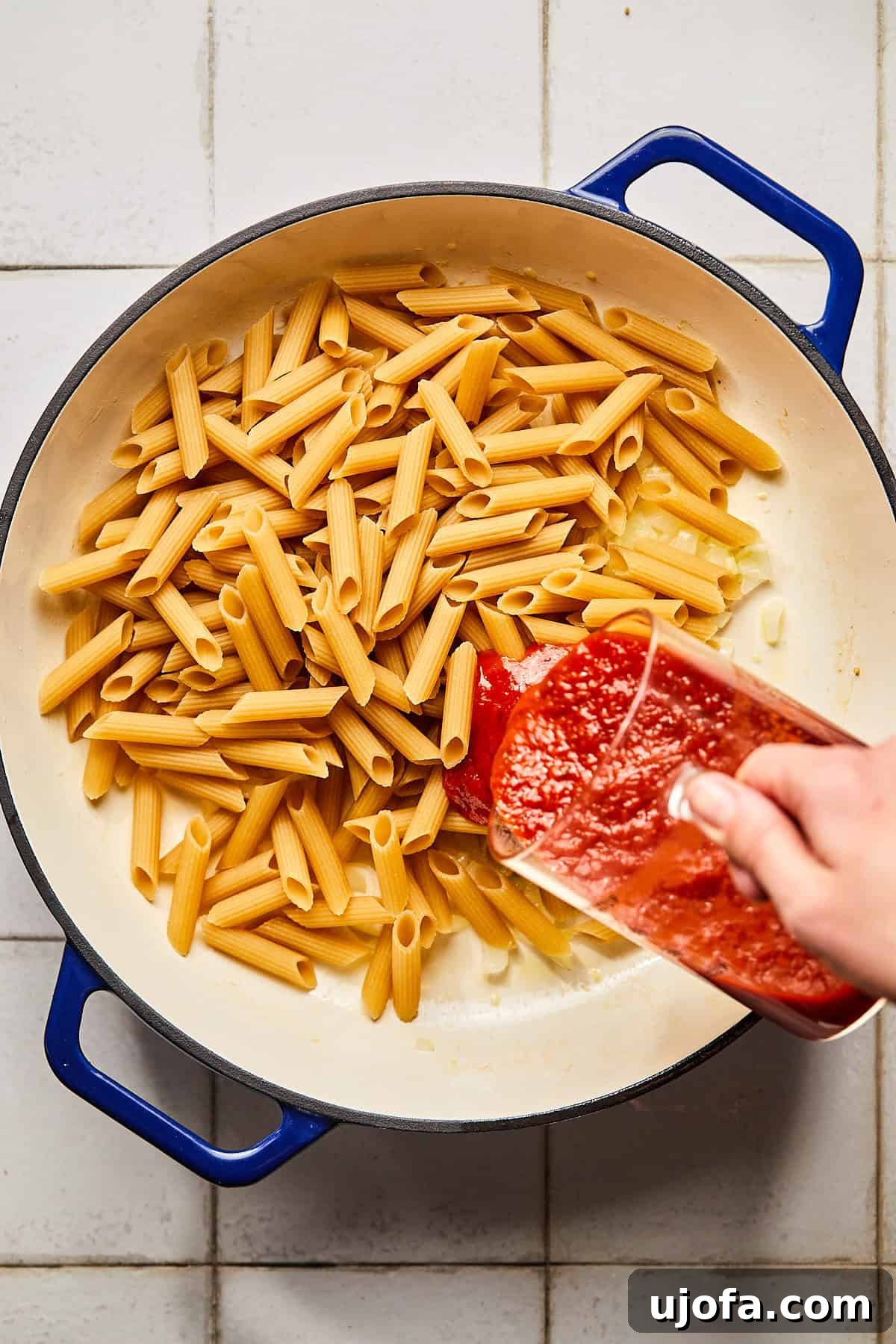 pasta in a pot with sauce being poured in 
