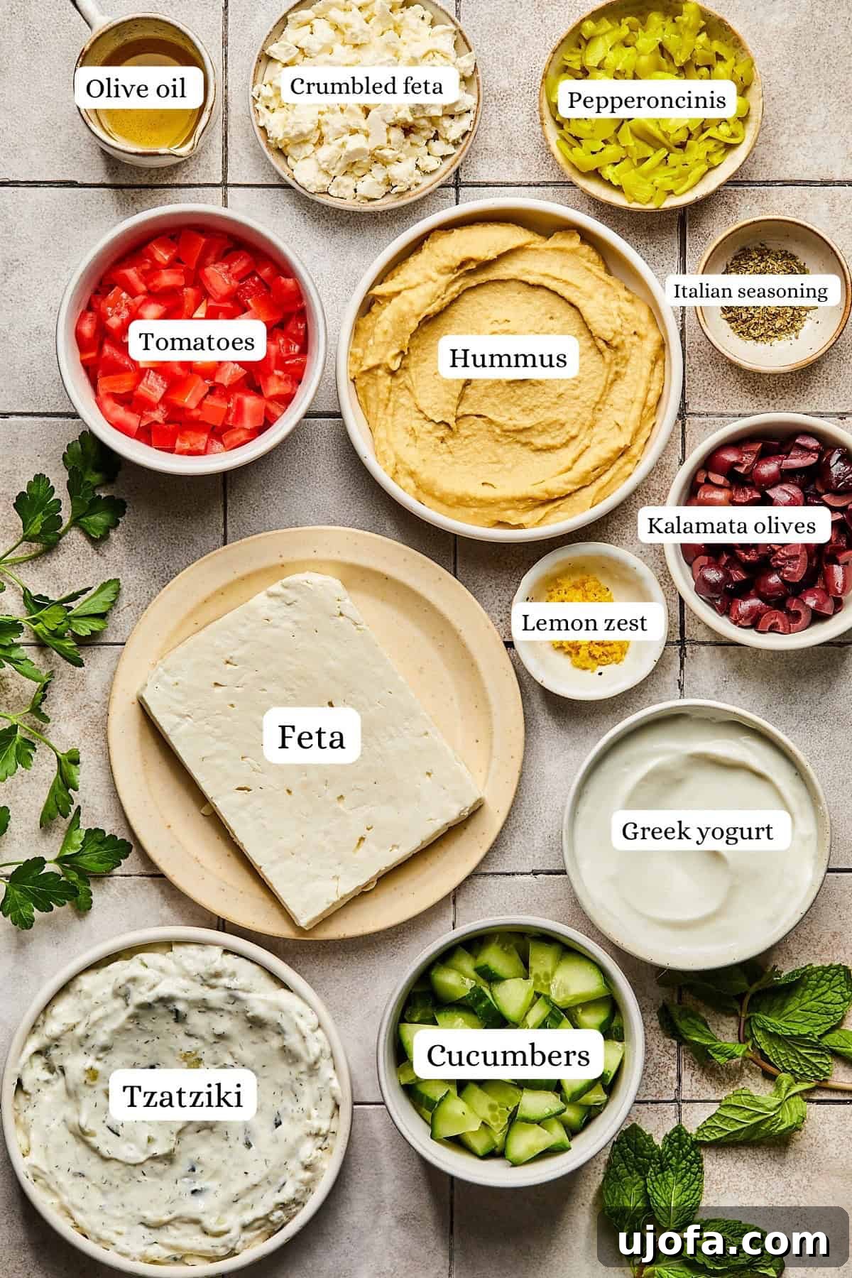 Individual bowls containing fresh ingredients for Greek dip, including feta, yogurt, and vegetables, arranged artfully.