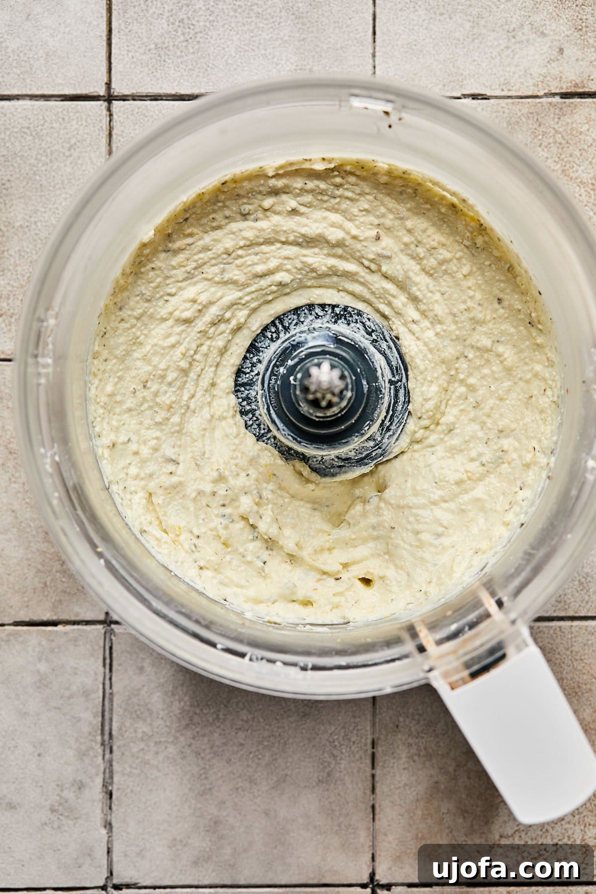 The food processor actively whipping feta, Greek yogurt, and other ingredients into a smooth, creamy consistency.