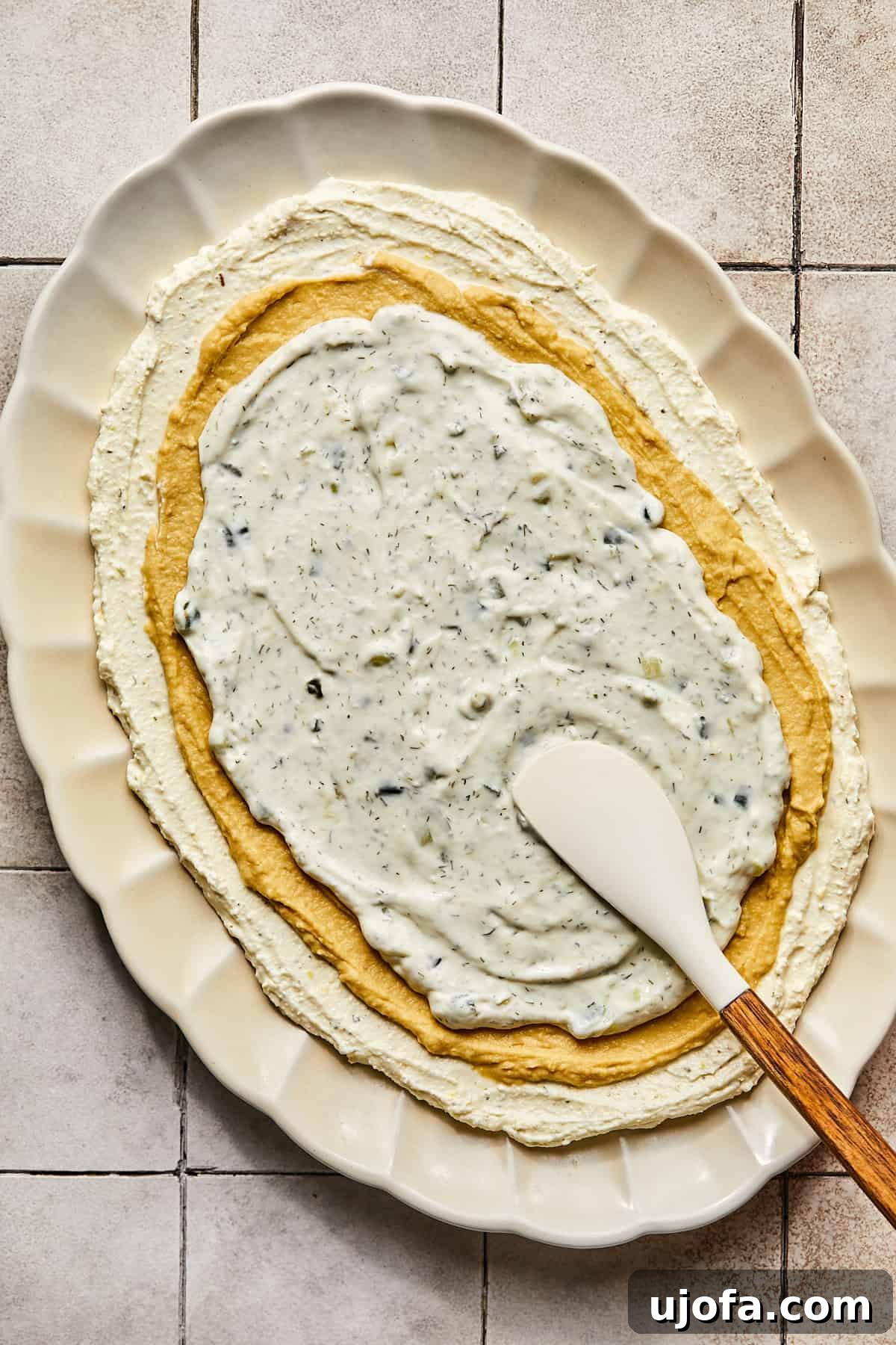 Whipped feta base topped with distinct layers of creamy hummus and refreshing tzatziki sauce.