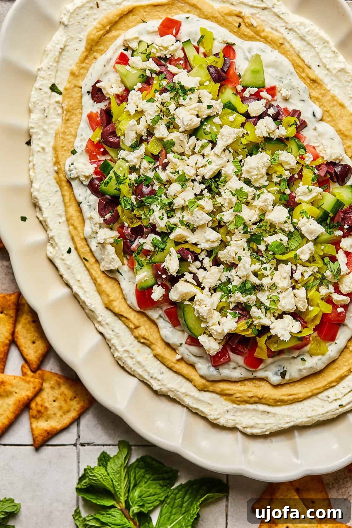 A vibrant Greek dip displayed on a platter, artfully surrounded by an abundance of crispy pita chips, inviting guests to enjoy.