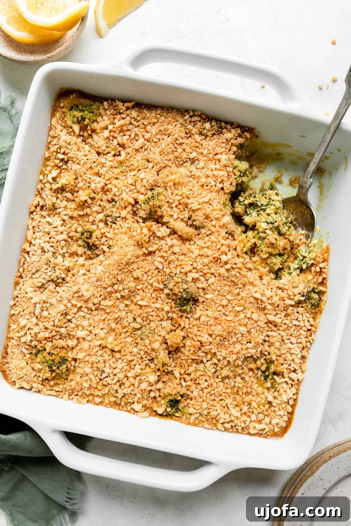 gluten free broccoli casserole in a white dish with a silver spoon scooping out a serving