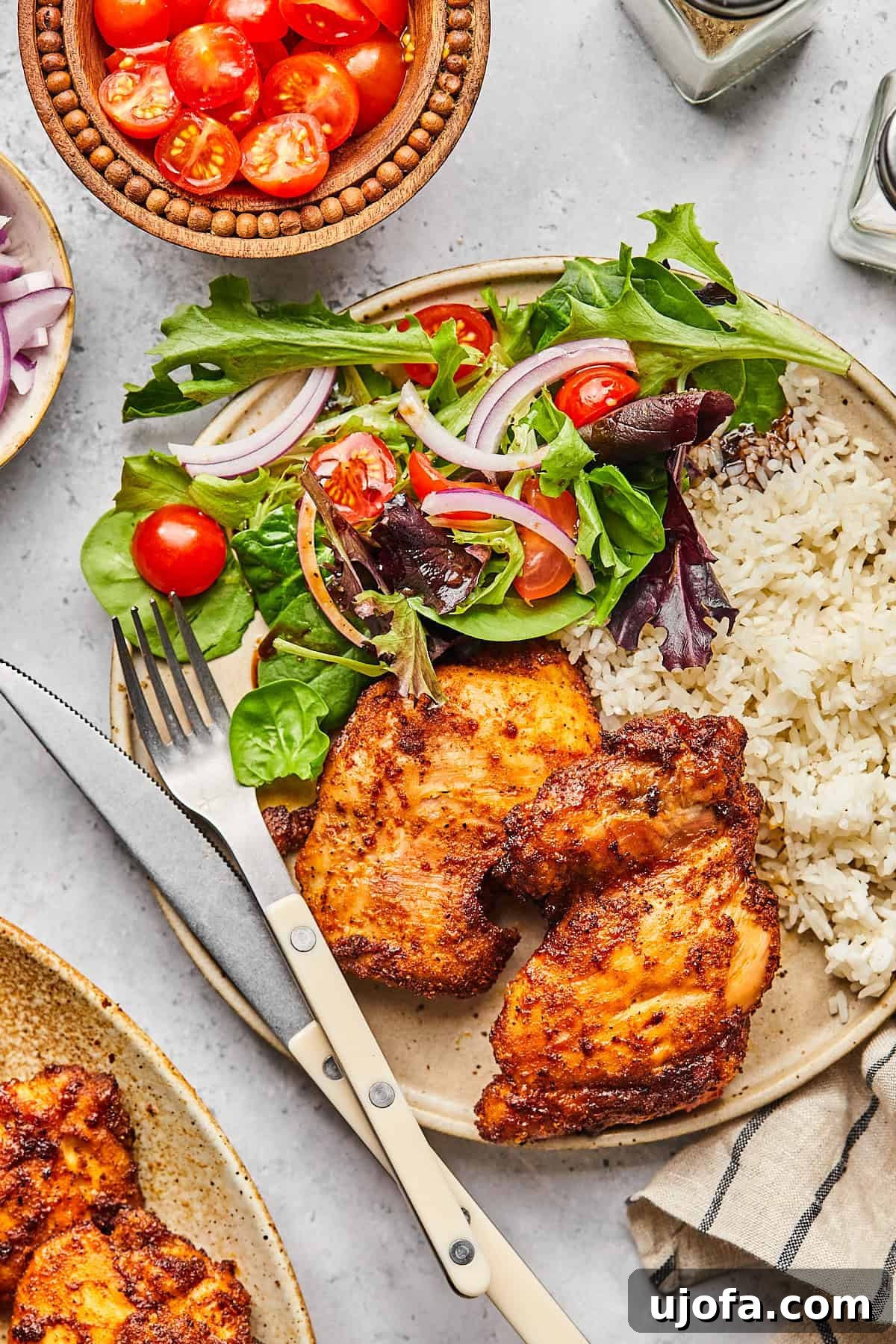 Crispy Juicy Air Fryer Boneless Thighs 11 a plate of boneless chicken thighs served with rice and salad
