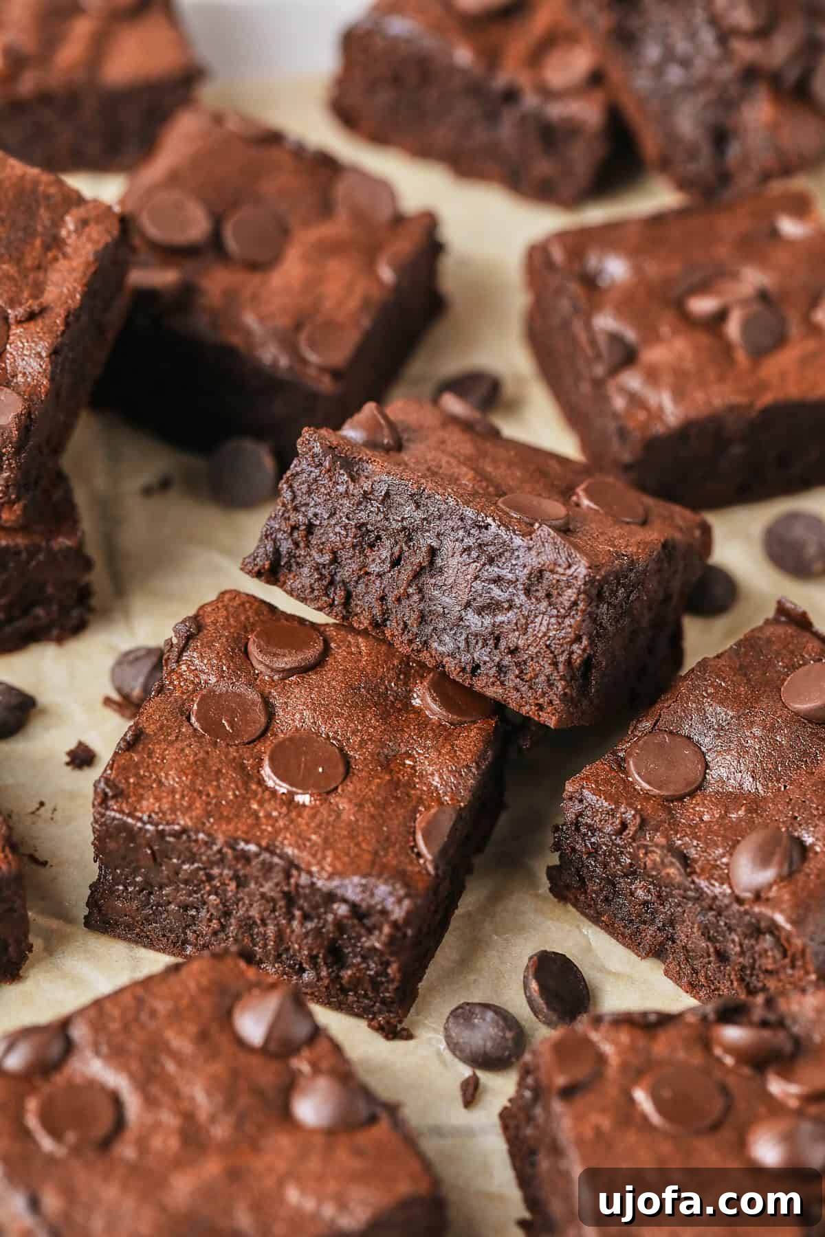 fudgy brownies sliced and stacked near each other on parchment paper