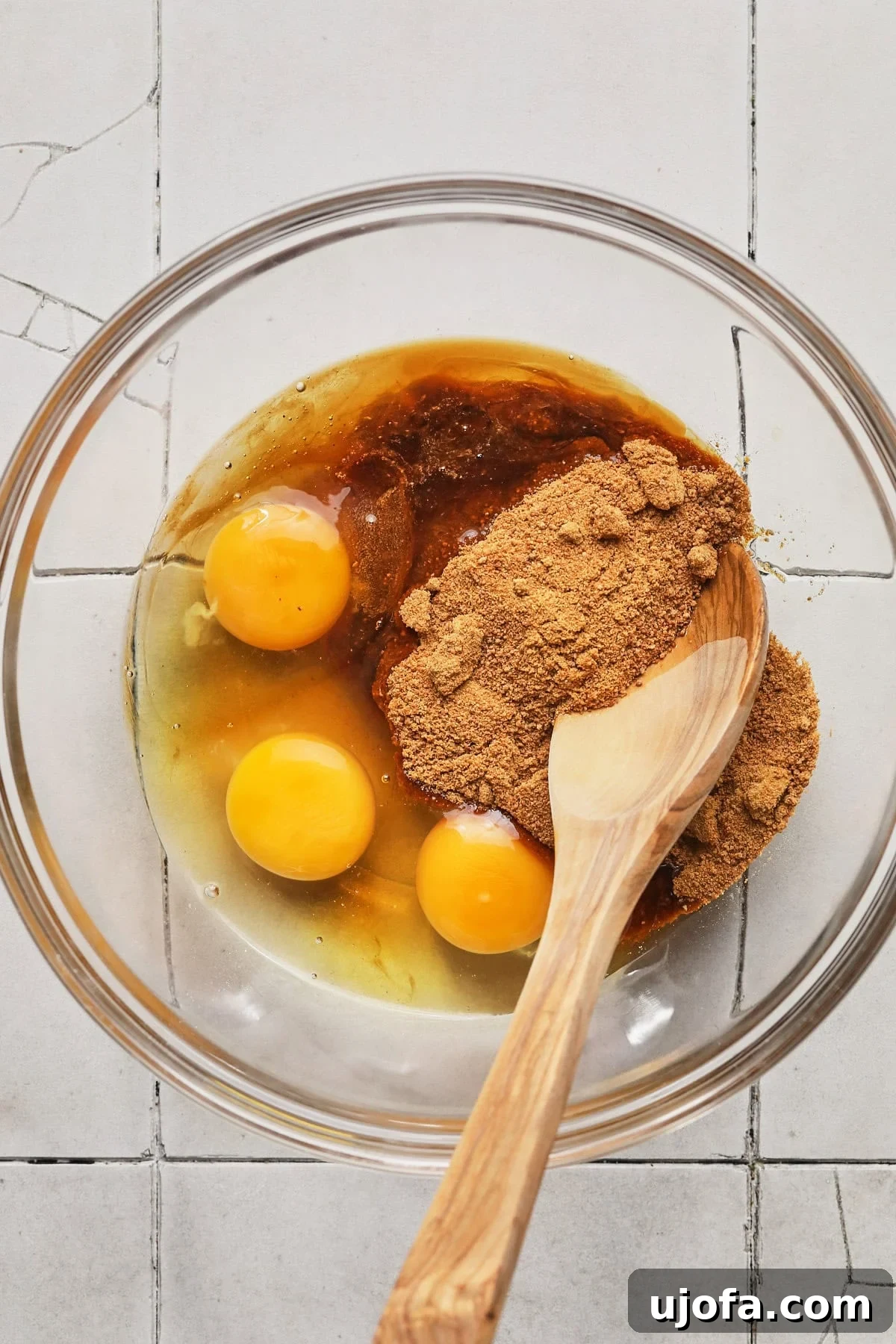 Mixing eggs, coconut sugar, and vanilla into a glass bowl.