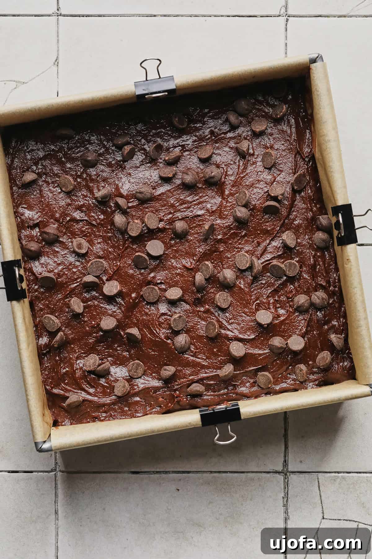 Spreading protein brownie batter into a baking pan and topping with chocolate chips before baking