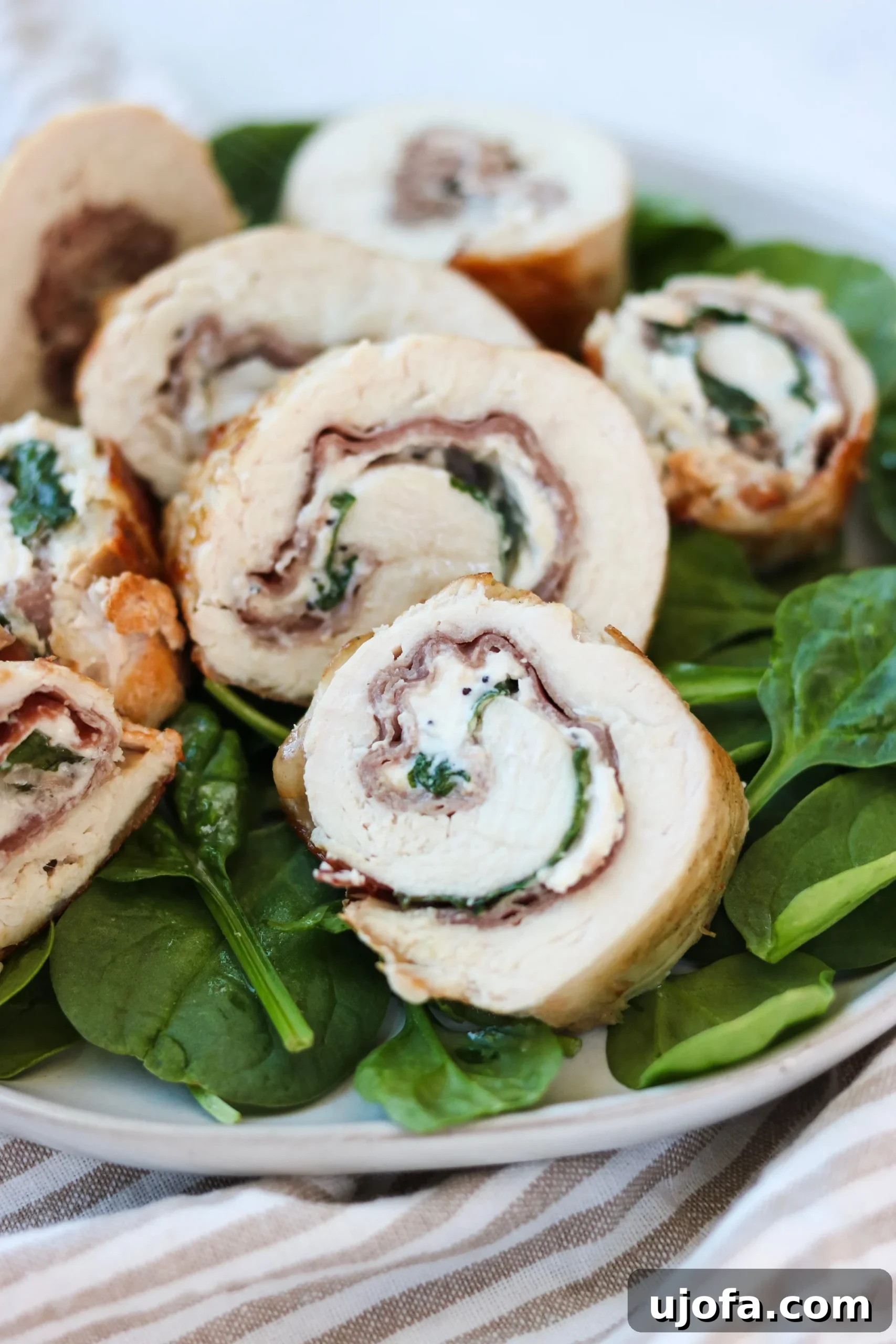 Close-up of a chicken breast stuffed with prosciutto, cream cheese, and basil, ready to be rolled and cooked.