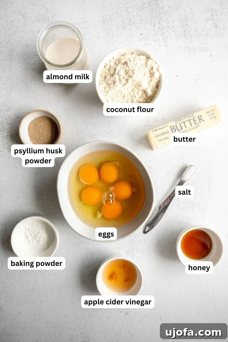 Various ingredients for baking coconut flour bread, including eggs, butter, milk, honey, coconut flour, and baking powder, laid out on a kitchen counter.
