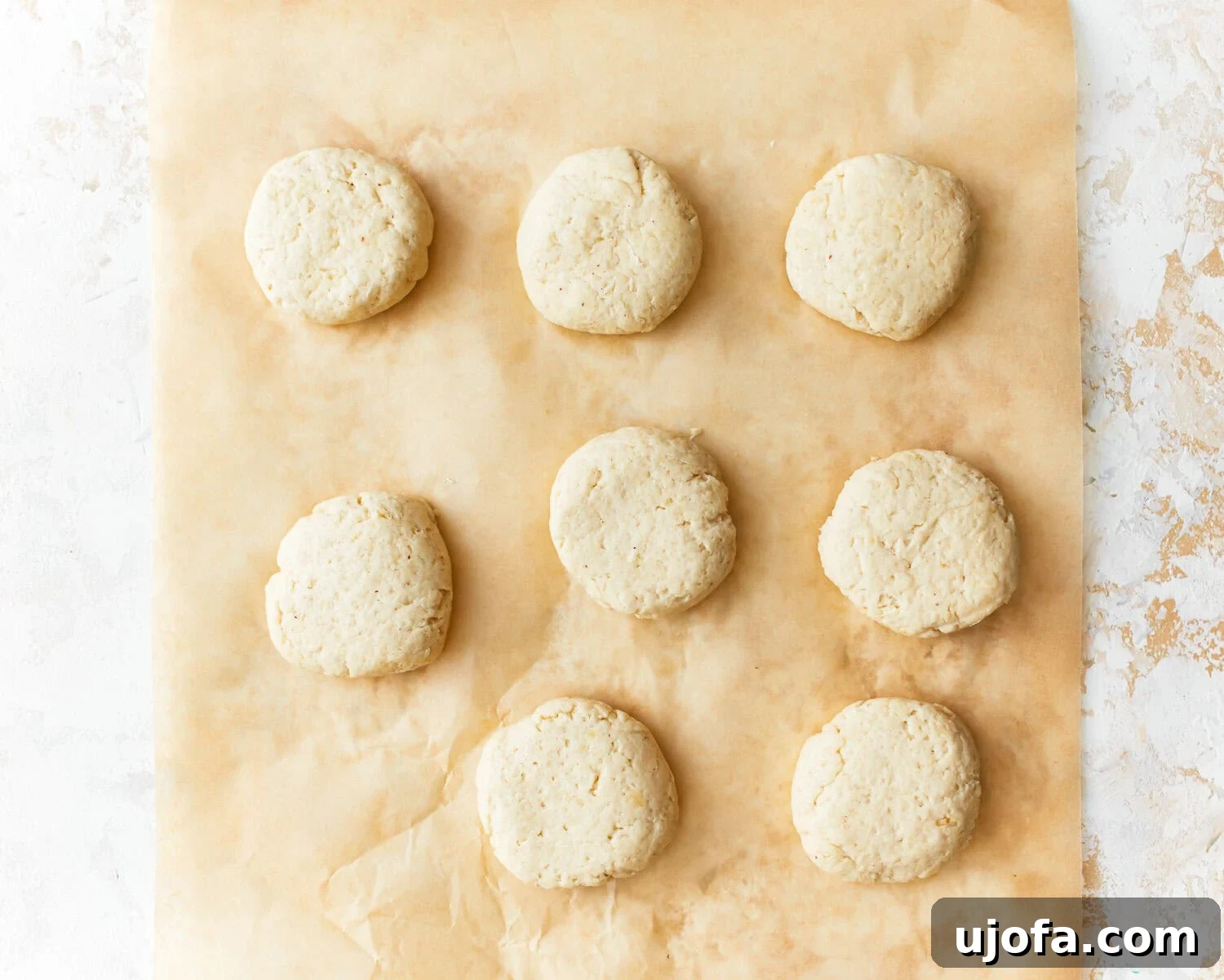 Almond flour tortillas dough portioned into eight balls on a parchment-lined surface.